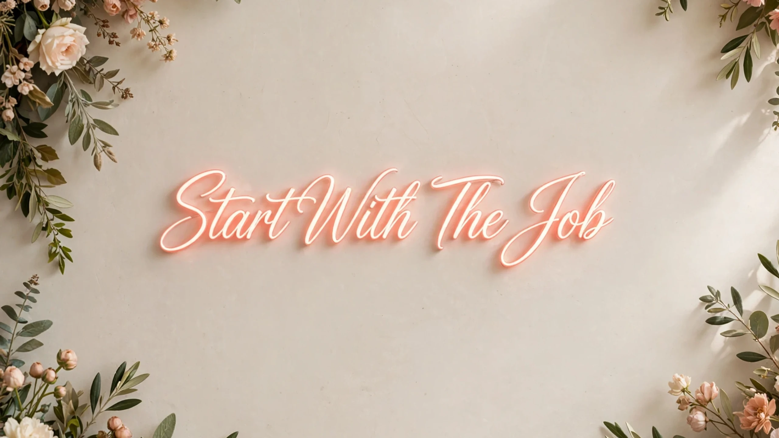 Neon script reading Start With The Job framed by foliage.